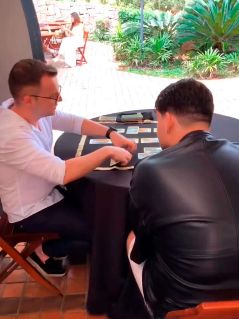 Guilherme Biotto conduzindo atendimento de tarô ao ar livre durante evento.