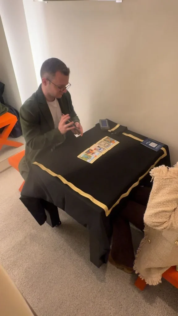Guilherme Biotto realizando leitura de tarô em mesa durante evento.